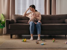 Mother experiencing stay-at-home-mom depression sitting on a couch holding a baby