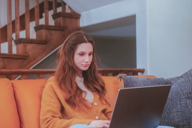 Youn teen on her laptop sitting on an orange couch