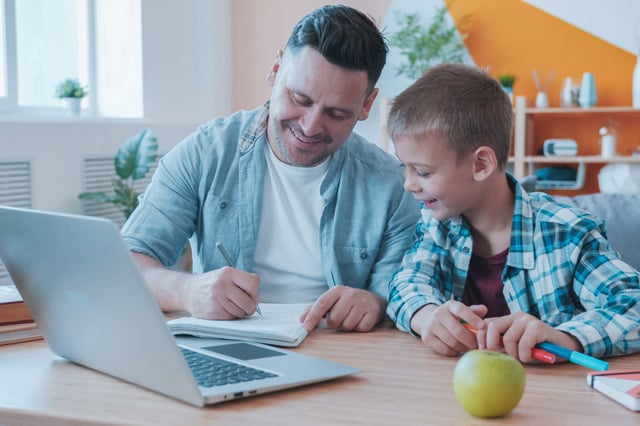dad and son in the kitchen smiling at the desk in front of a computer