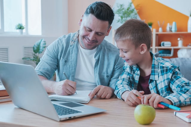 dad and son in the kitchen smiling at the desk in front of a computer
