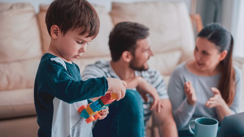 Child playing with toys while parents talk in the background