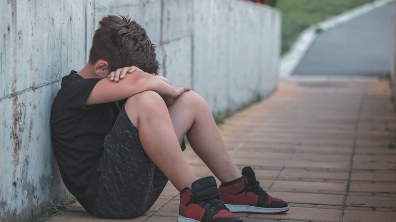 Kid sitting against wall crying from bullying