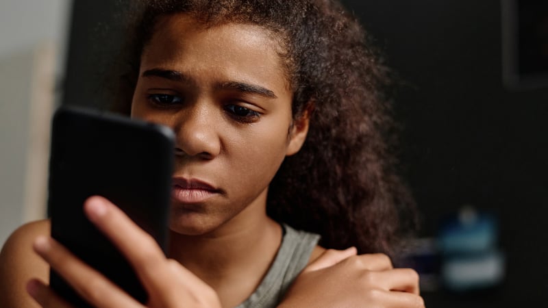Teenage girl looks at her phone dejectedly like she's just been rejected