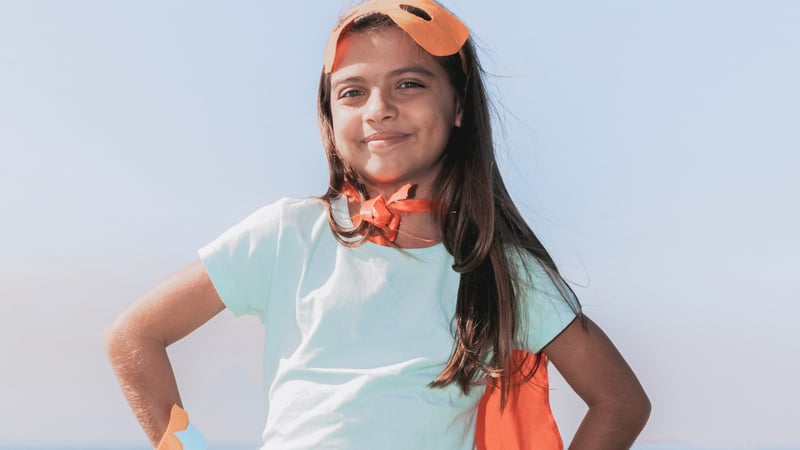 Kid smiling confidently wearing a superhero costume