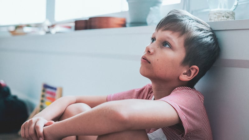 Kid with anxiety sitting on the ground looking up