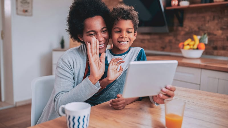 mom and son smiling and waving at computer while in the kitchen