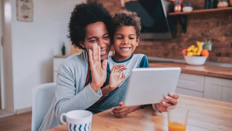 mom and son smiling and waving at computer while in the kitchen