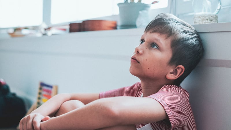 Kid with anxiety sitting on the ground looking up