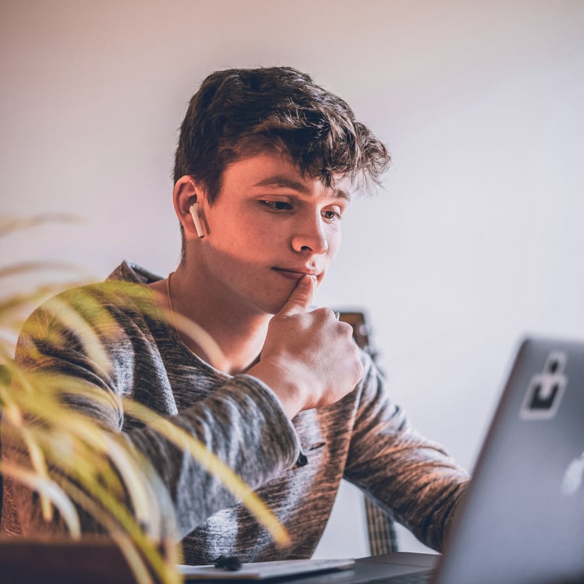 teenage boy with earbuds in at the computer
