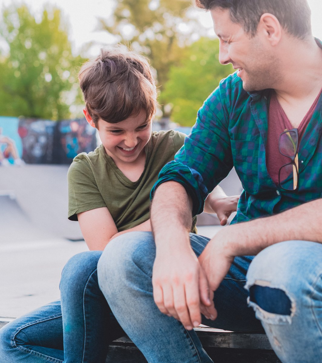 Dad and his son hanging out in a skate park
