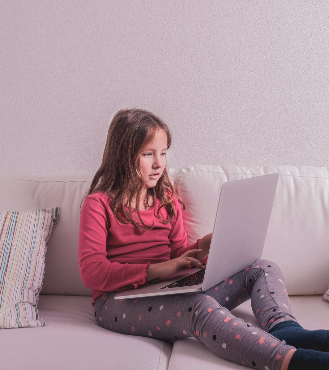 young girl on the couch smiling during a therapy session on the computer