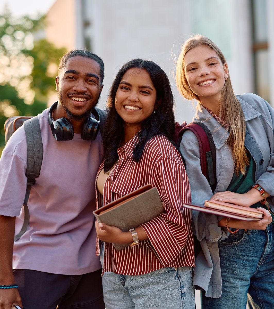 Group of happy students at university campus looking at camera.