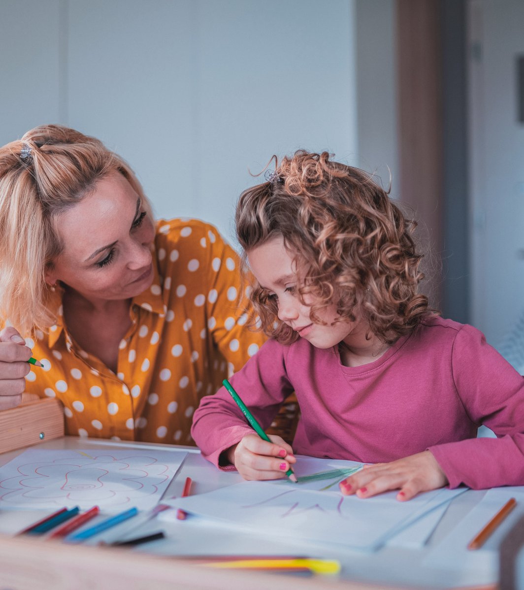 Mom and daughter drawing on a piece of paper on a table