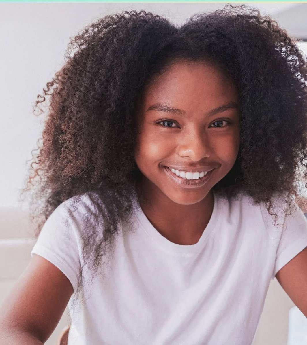 Young African American teen smiling at the camera in a white shirt