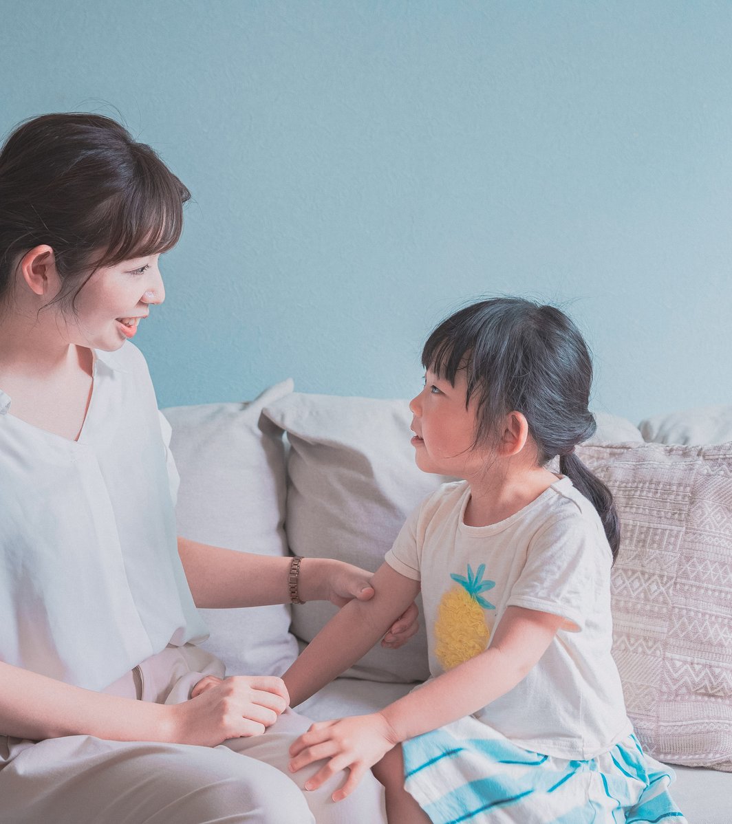 Mom and daughter sitting on a couch talking