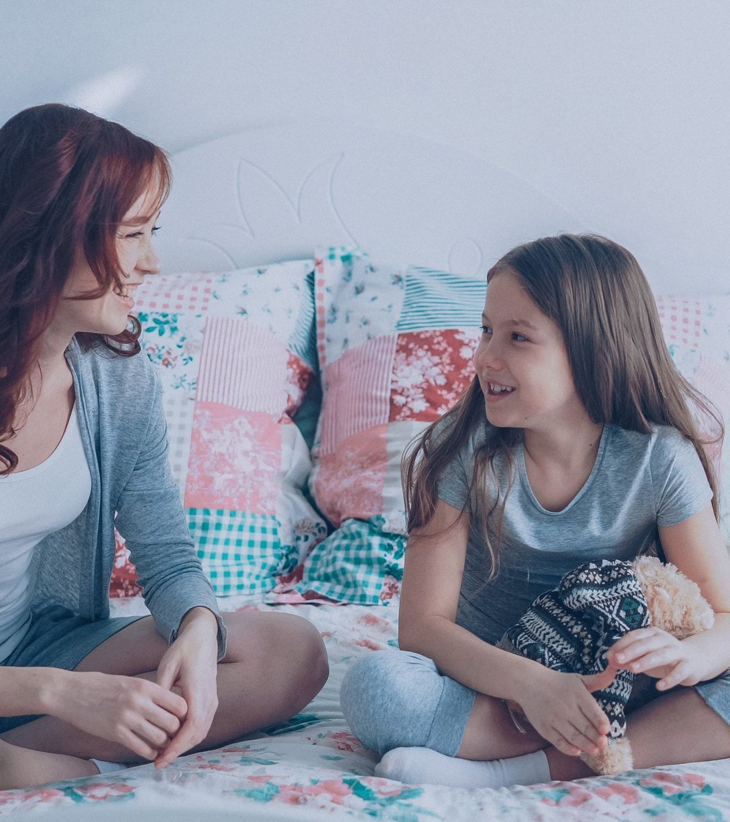 Mom and daughter talking on a bed