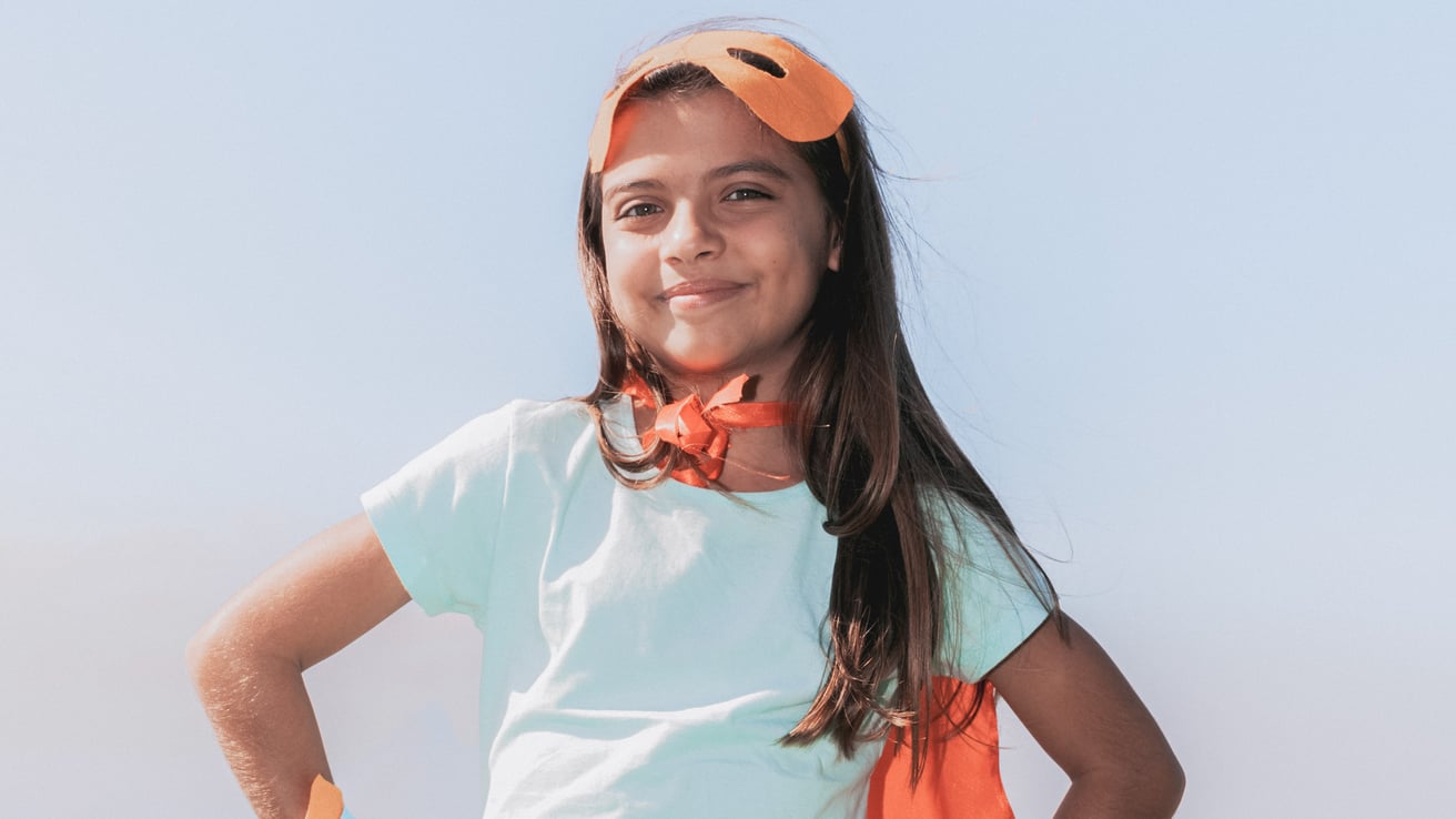 Kid smiling confidently wearing a superhero costume