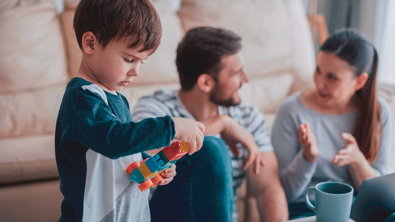 Child playing with toys while parents talk in the background