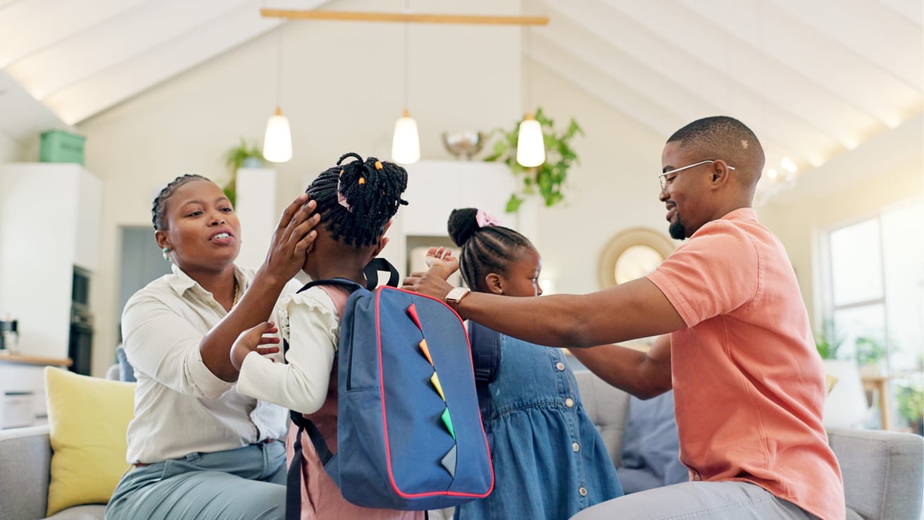 African American mom and dad getting their two young daughters ready for school