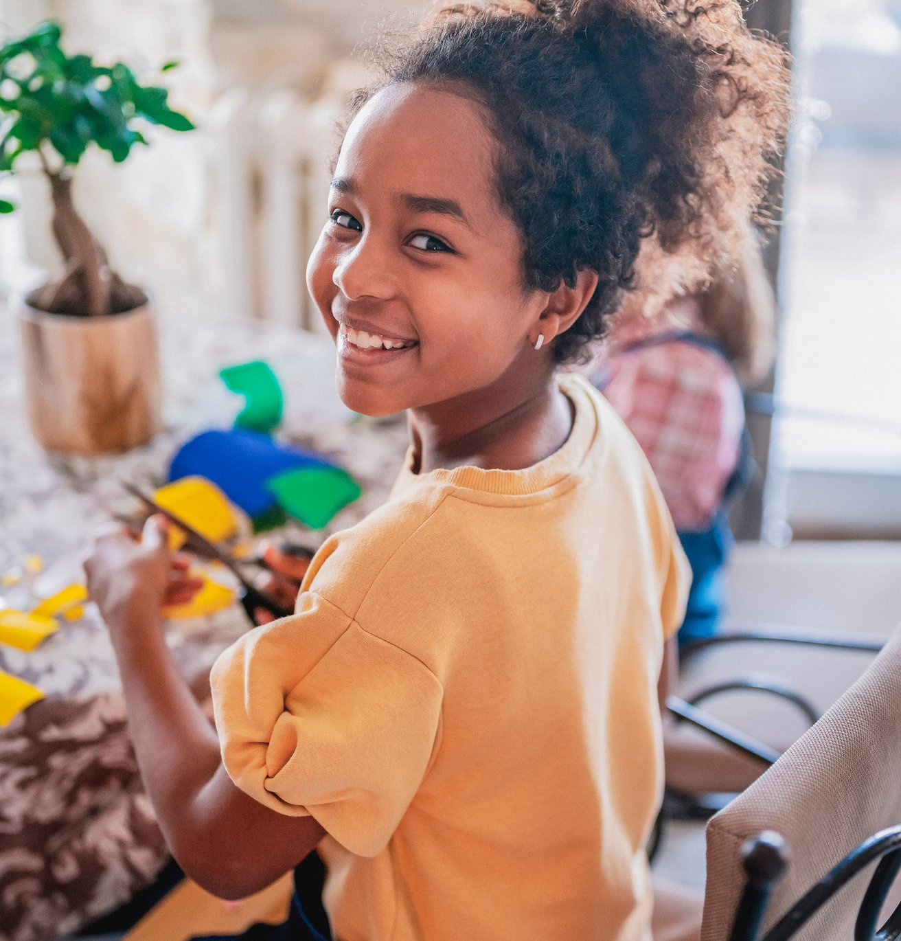 Little girl doing a craft at her kitchen table