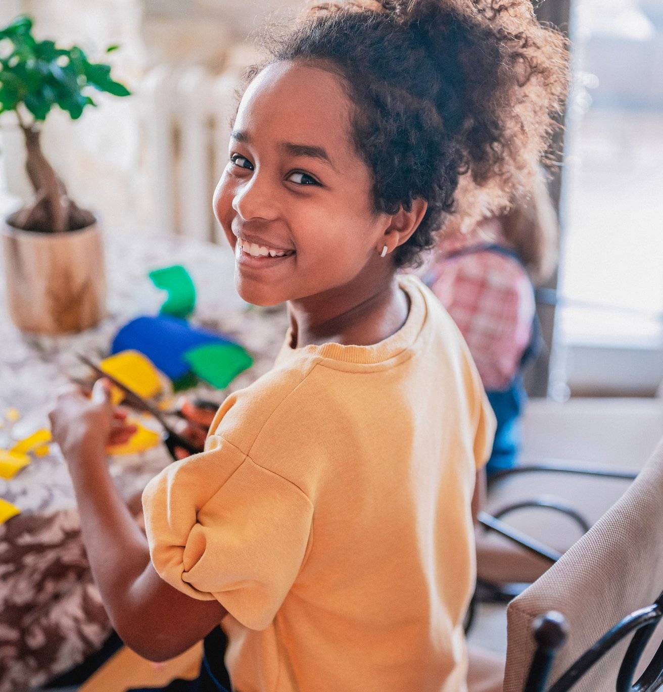 Little girl doing a craft at her kitchen table