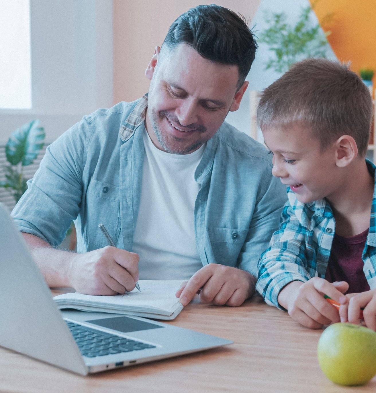 dad and son in the kitchen smiling at the desk in front of a computer
