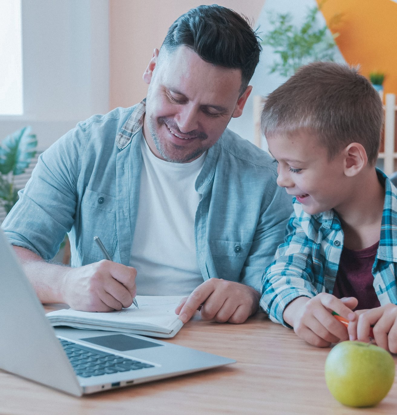 dad and son in the kitchen smiling at the desk in front of a computer