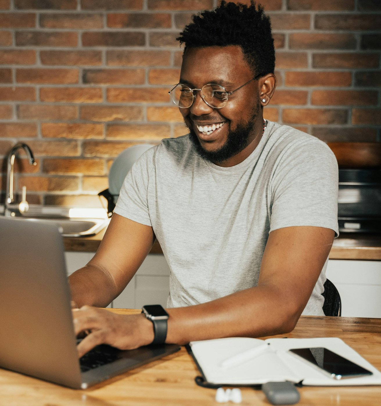 Youn adult male with facial hair and dark skin at his computer