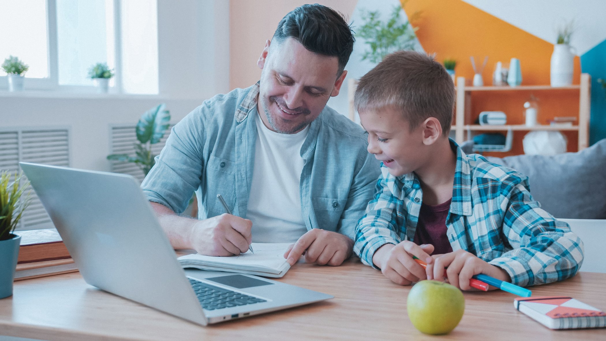 dad and son in the kitchen smiling at the desk in front of a computer