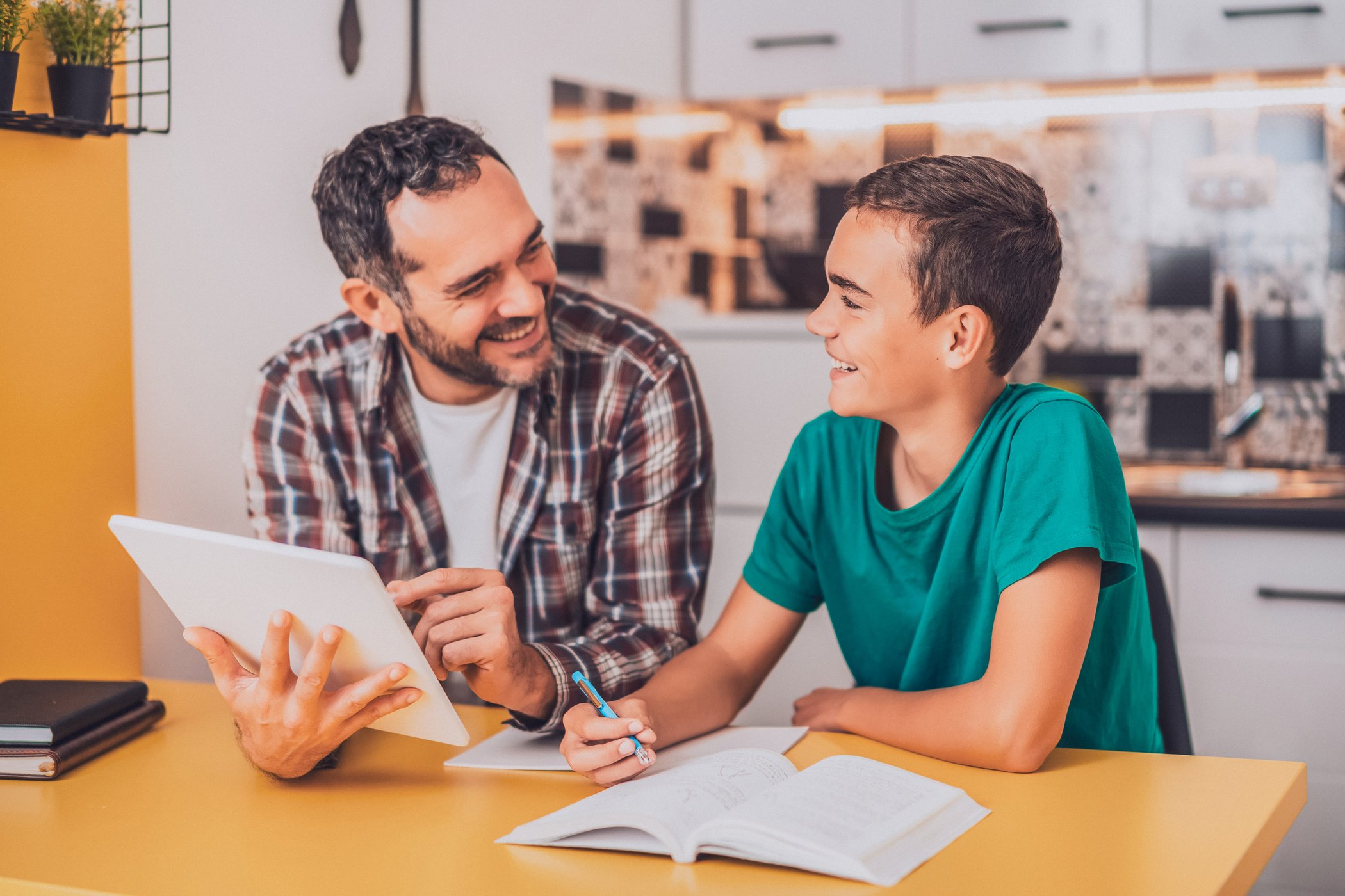 Father with his son, smiling with a tablet and book 