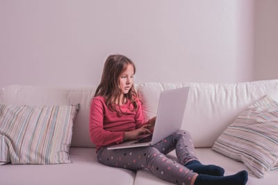 young girl on the couch smiling during a therapy session on the computer