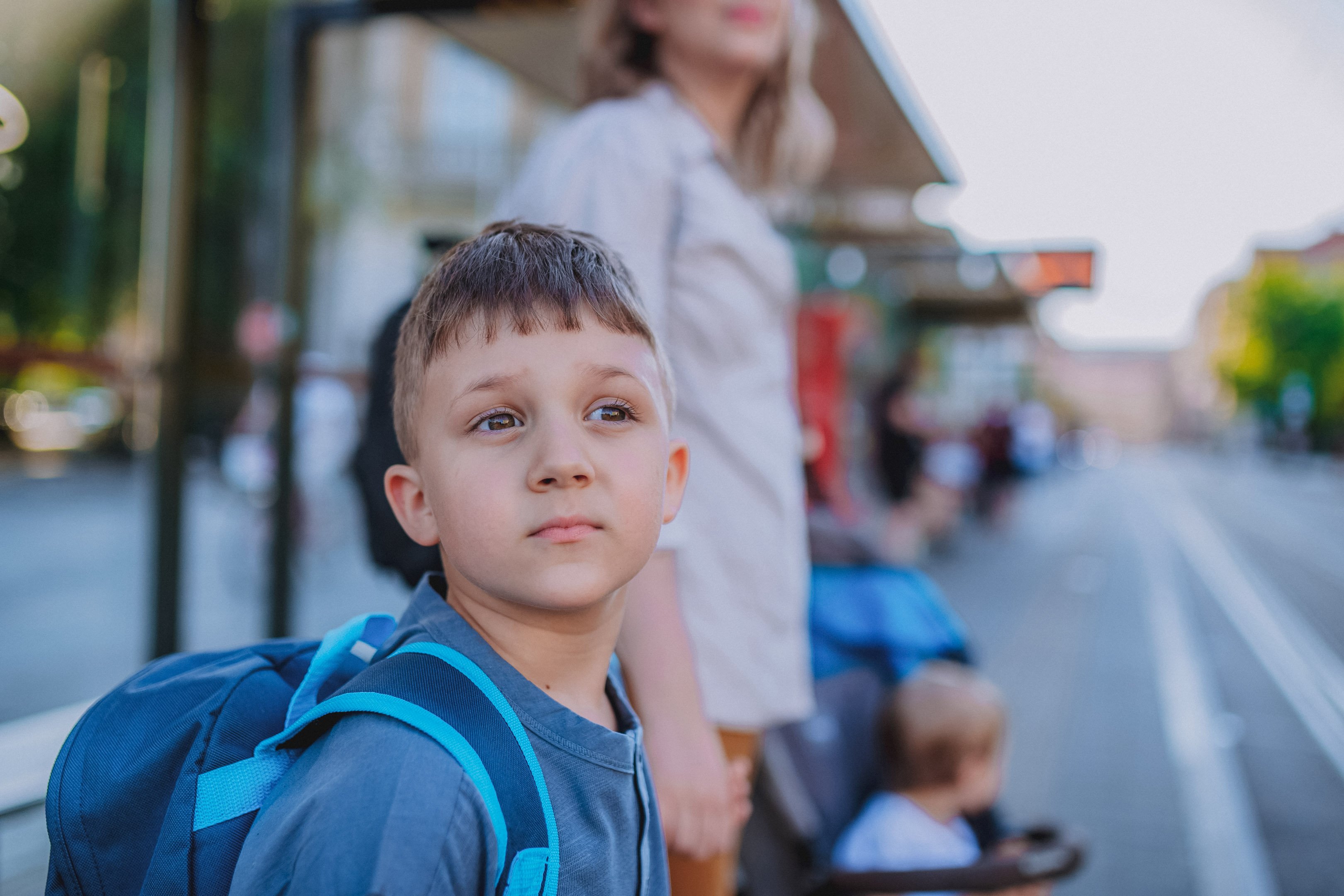Kid at bus stop with mom dealing with anxiety