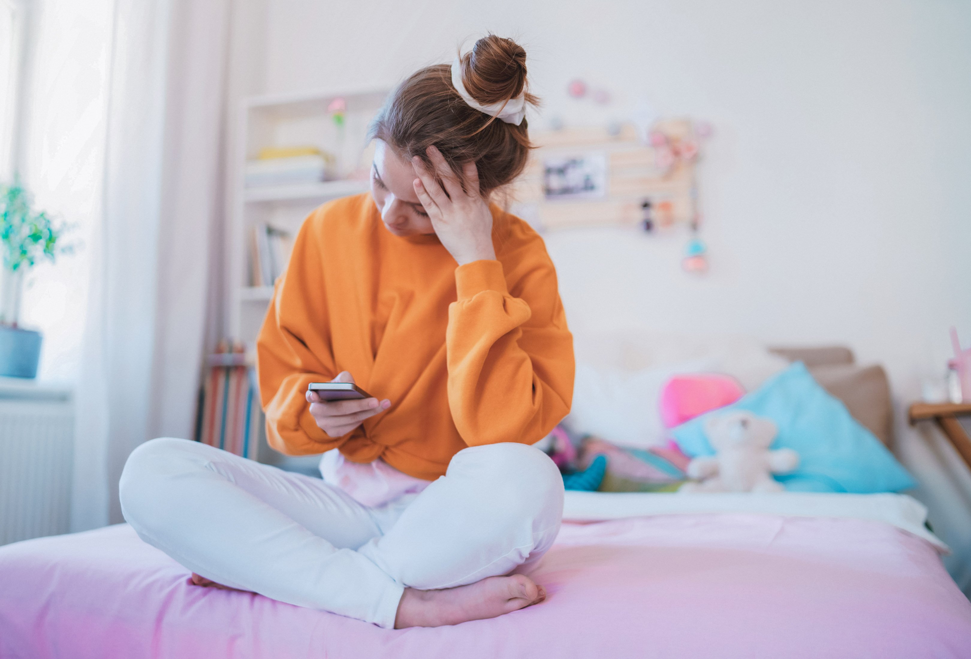 Girl scrolling through her phone on her bed