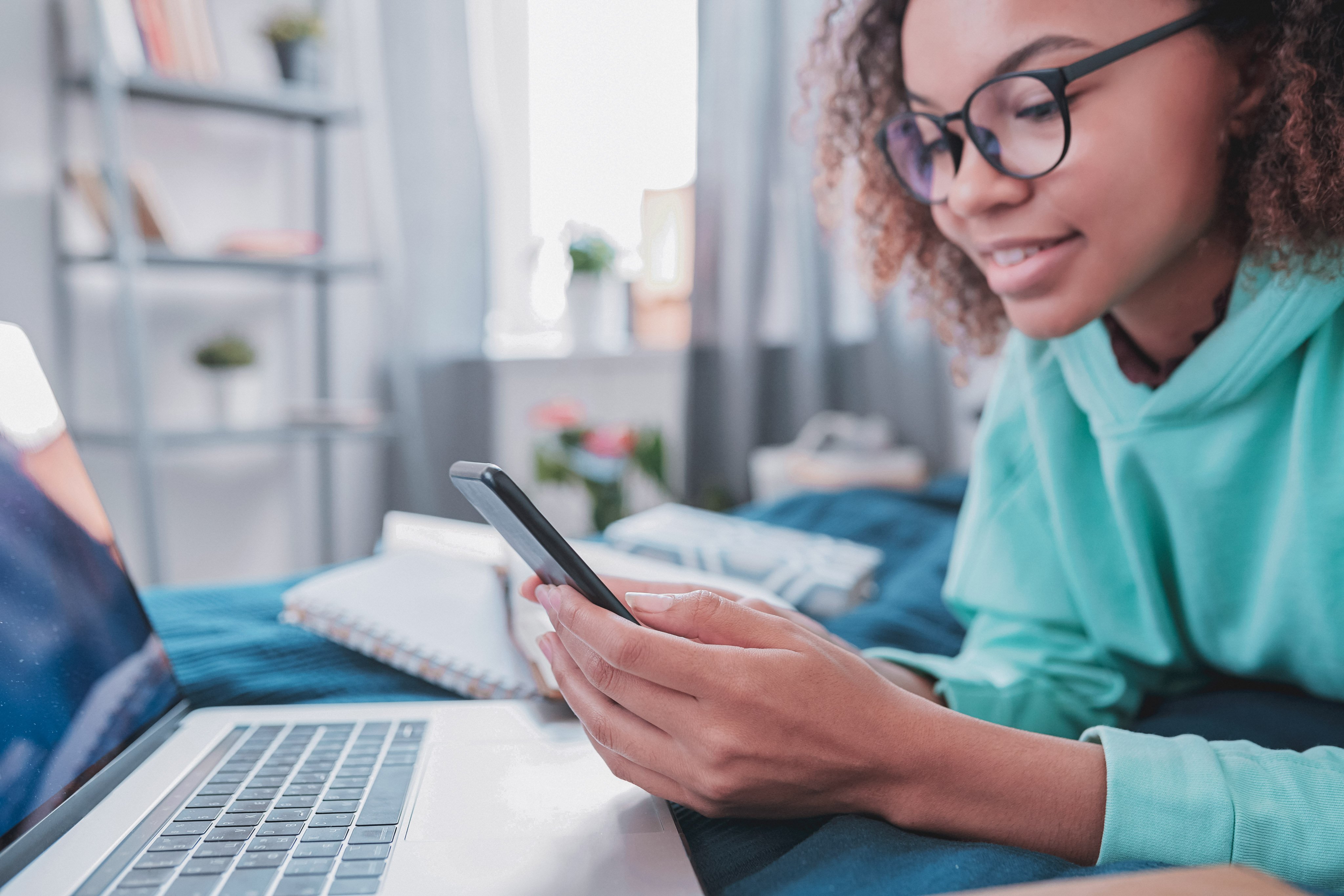Kid on phone on bed in front of her computer