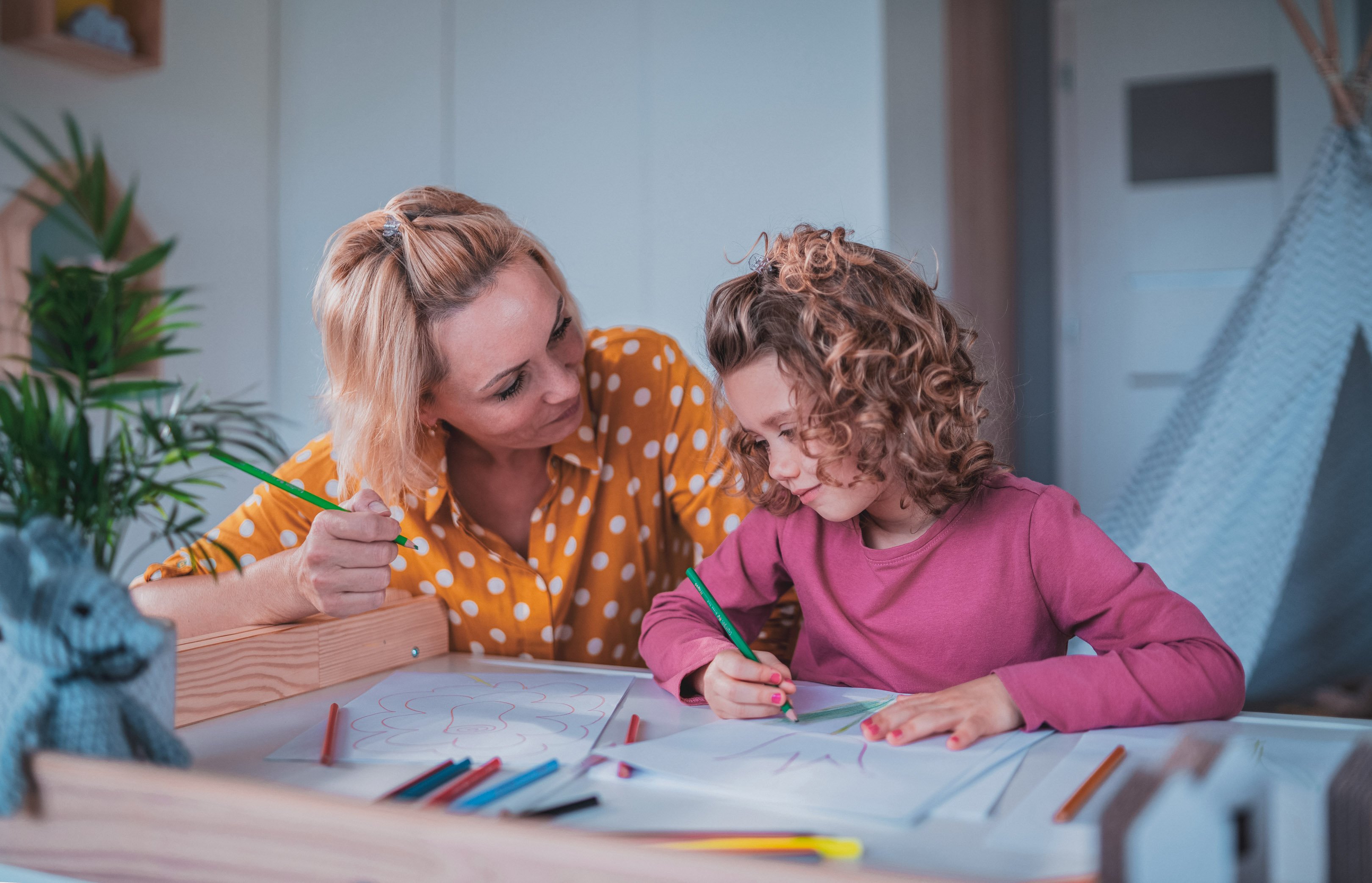 Mom and daughter drawing on a piece of paper on a table