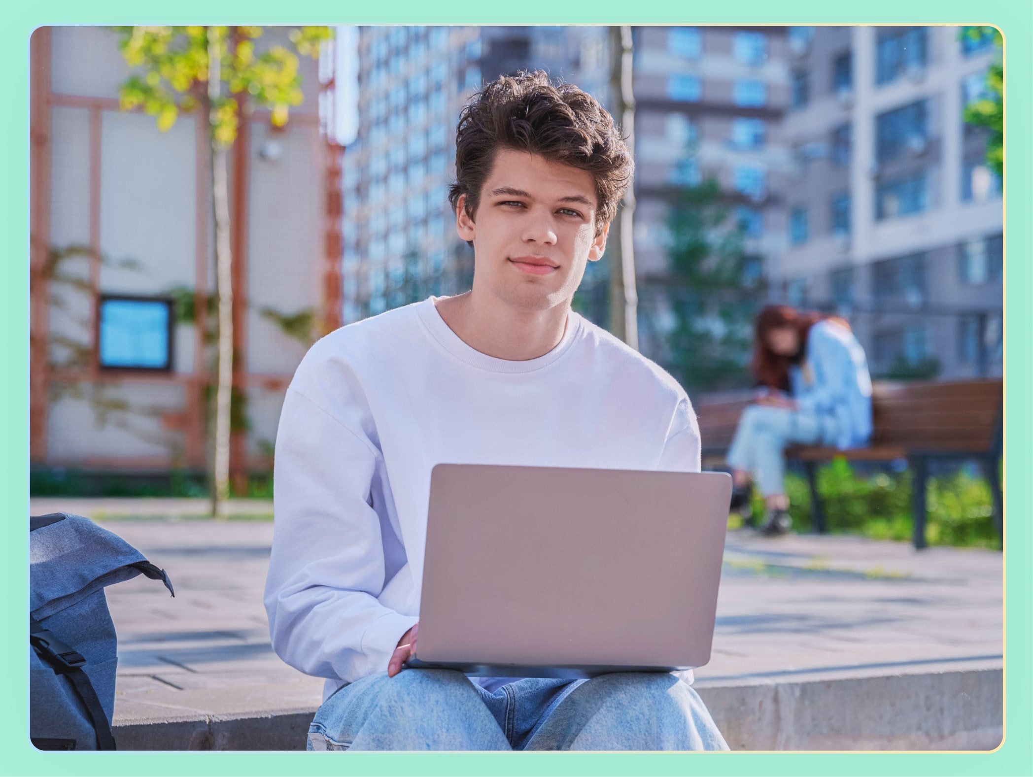 Young adult male in white shirt on a laptop outside
