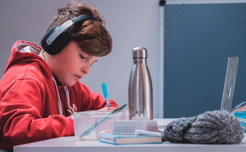 Kid with headphones that has adhd doing homework