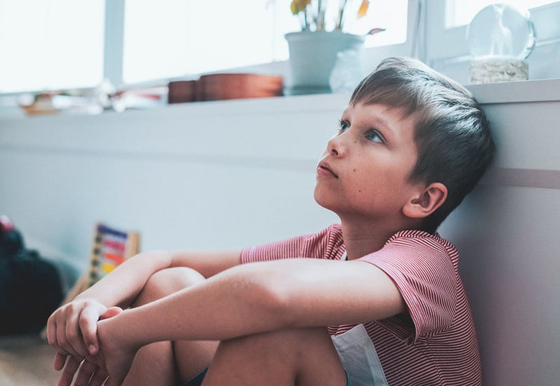 Kid with anxiety sitting on the ground looking up