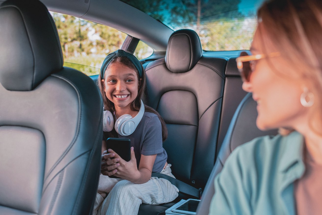 Child on her phone in the car with her mom