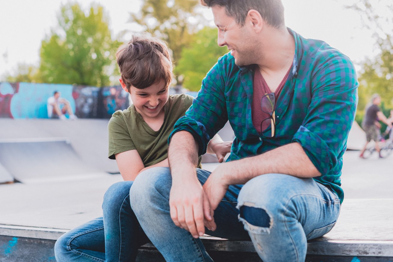 Dad and his son hanging out in a skate park
