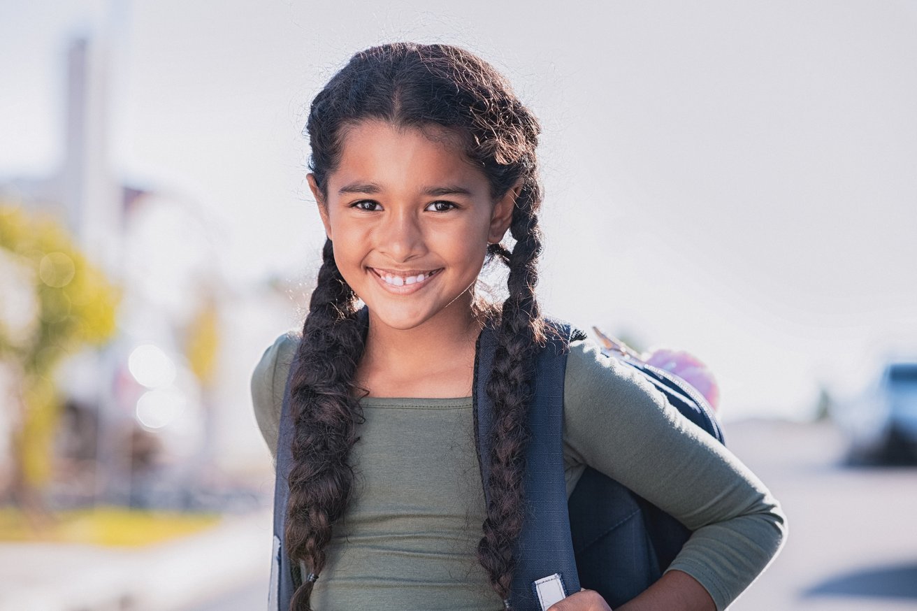 Young girl wearing a school backpack outdoors