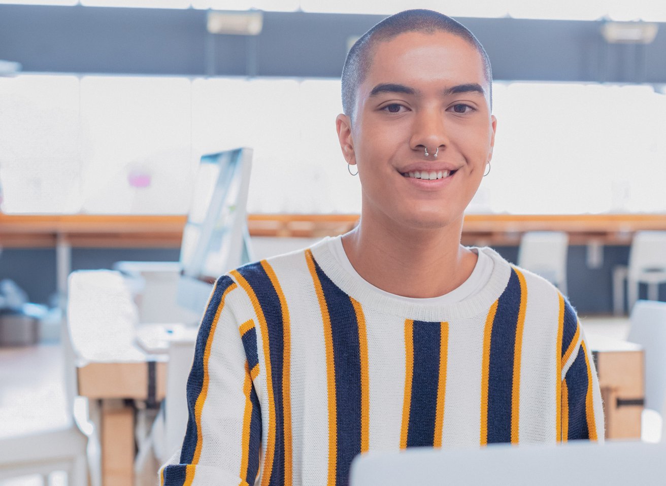 Young person at a coffee shop in a striped shirt