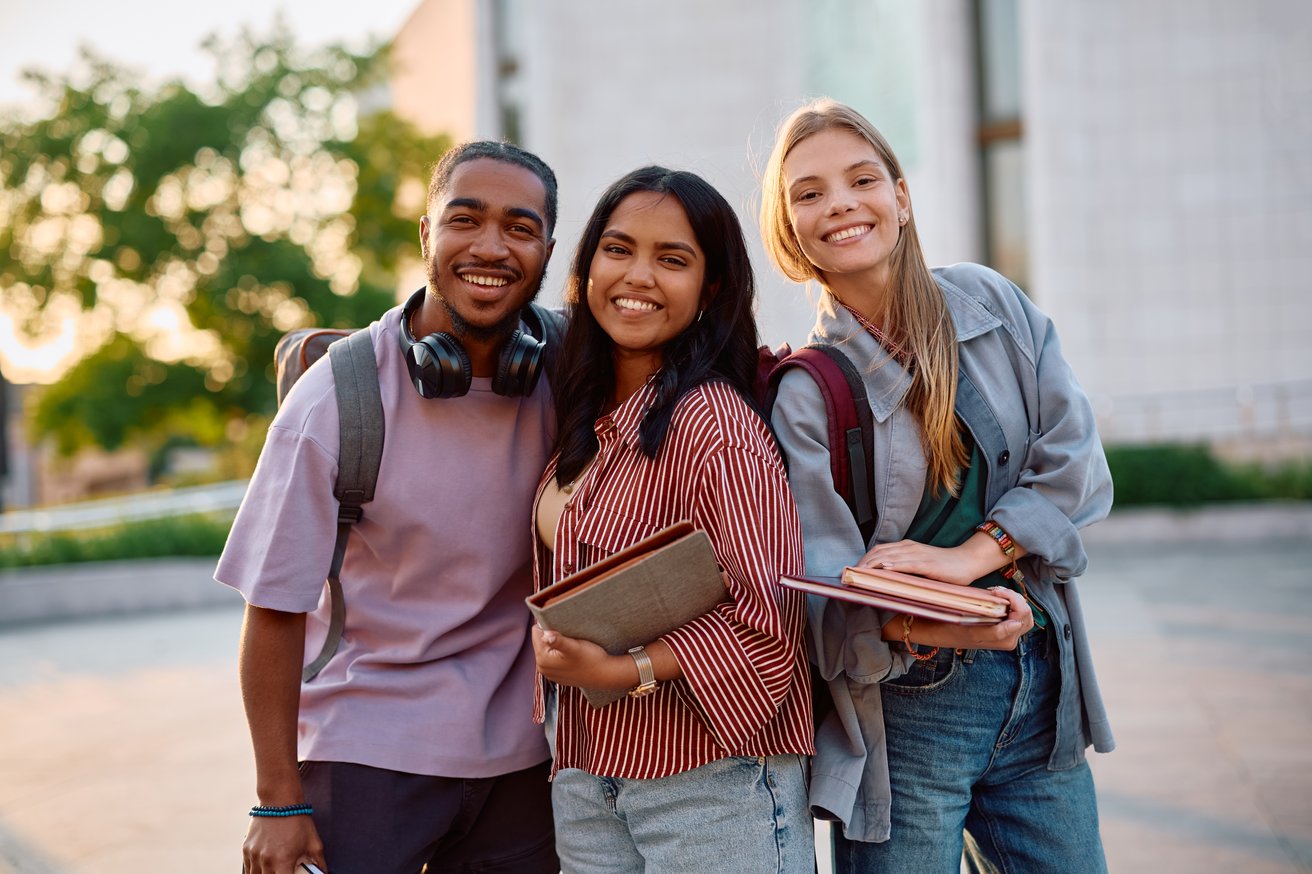 Group of happy students at university campus looking at camera.
