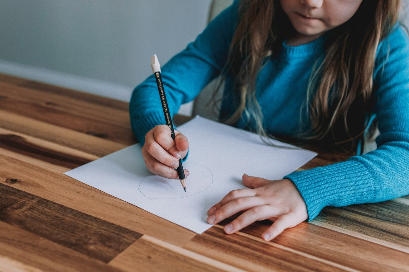 Kid drawing on paper with a pencil