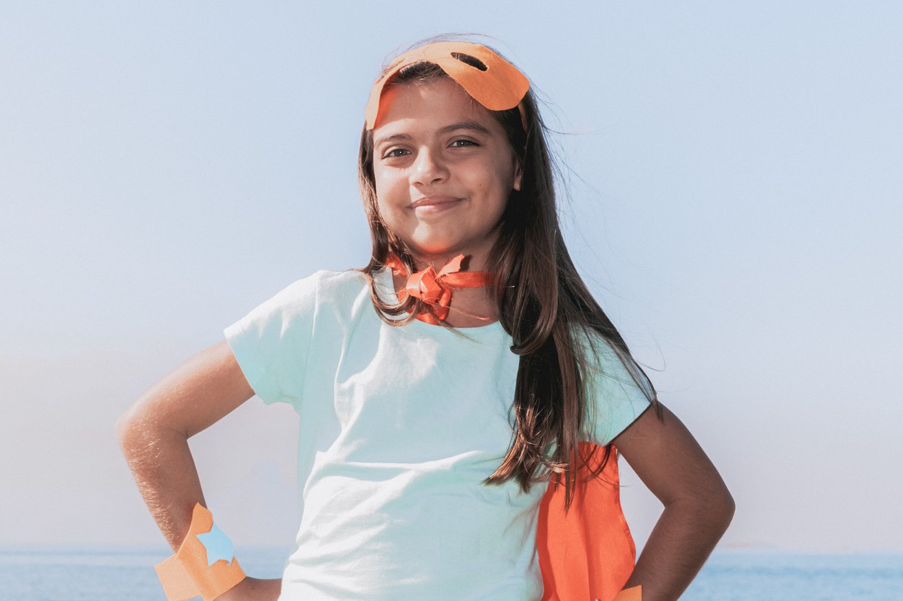 Kid smiling confidently wearing a superhero costume