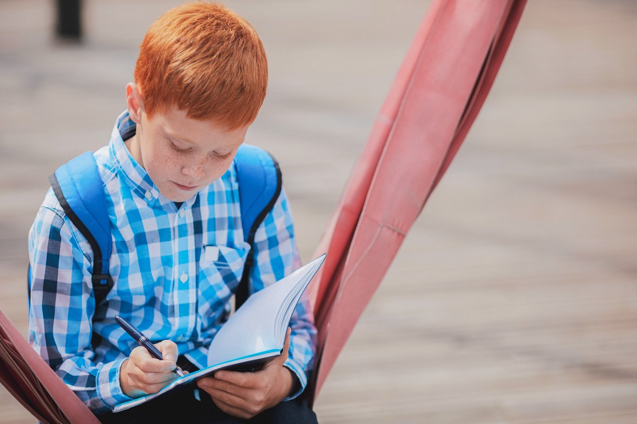 Little boy journaling in a hammock