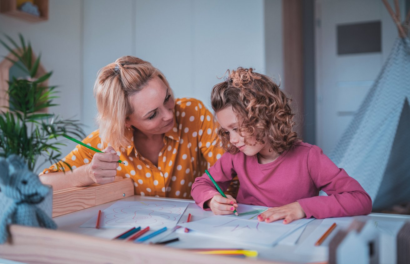 Mom and daughter drawing on a piece of paper on a table