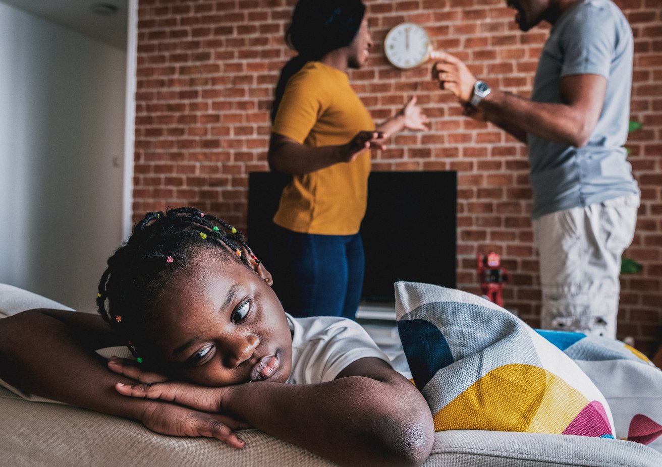 Parents arguing while daughter puts her head on a table