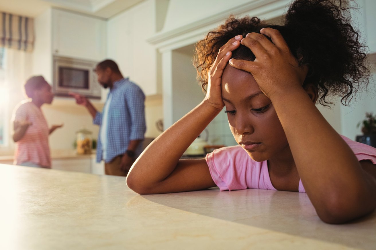 Frustrated young girl with parents in the background