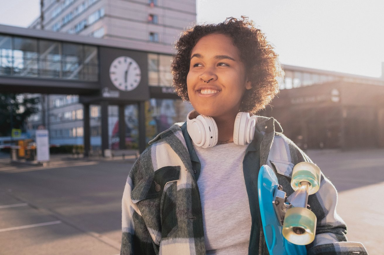 Teen girl walking outside holding a skateboard